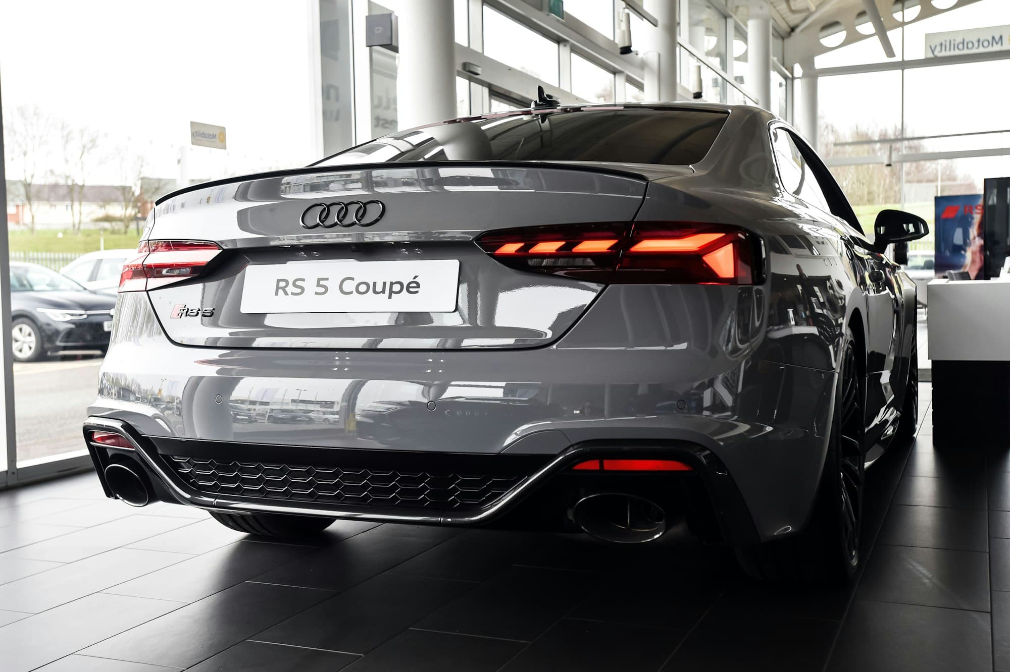 A grey Audi RS 5 Coupé on the showroom floor of an Audi dealership